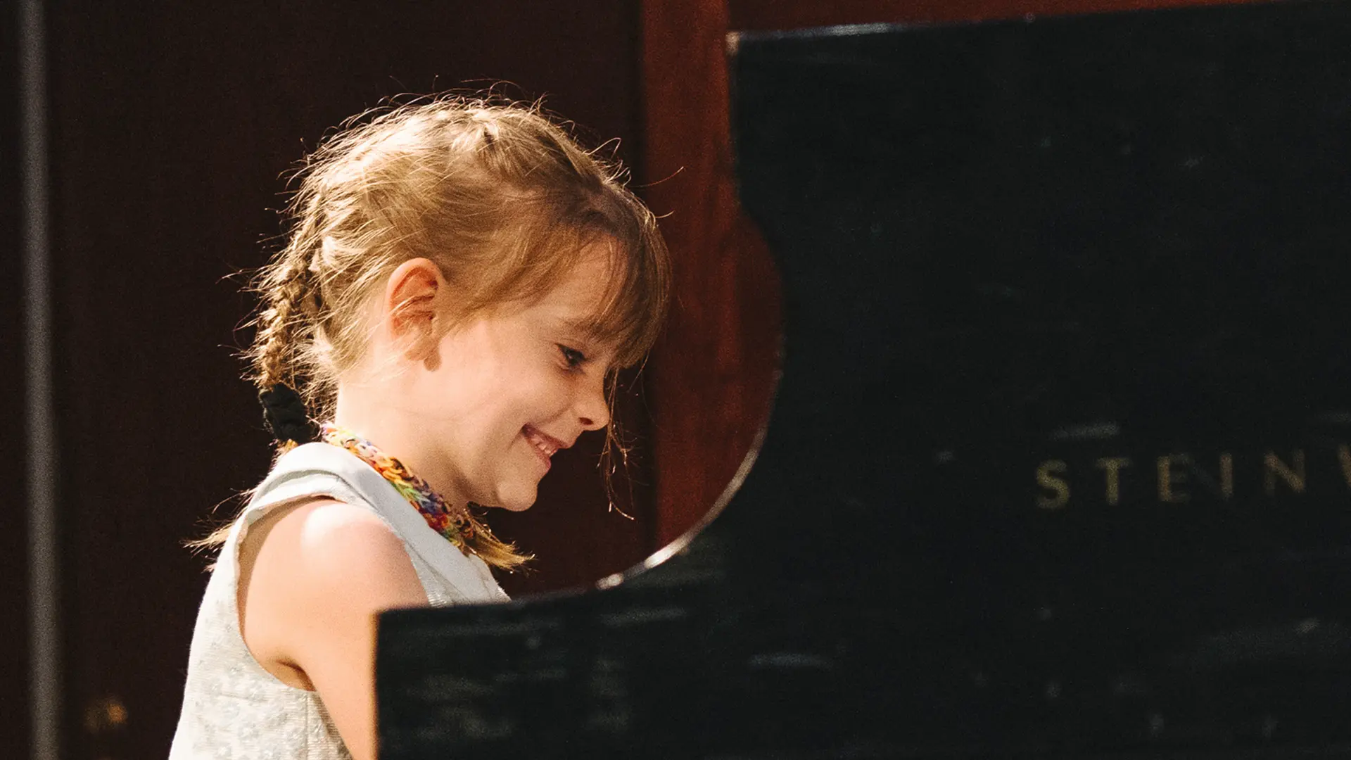 Piano lesson — student practicing at the piano with an instructor