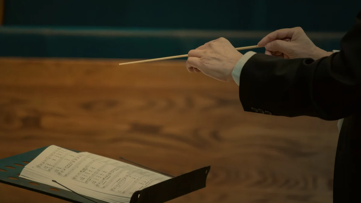 Close-up of a conductor's hands with baton and score