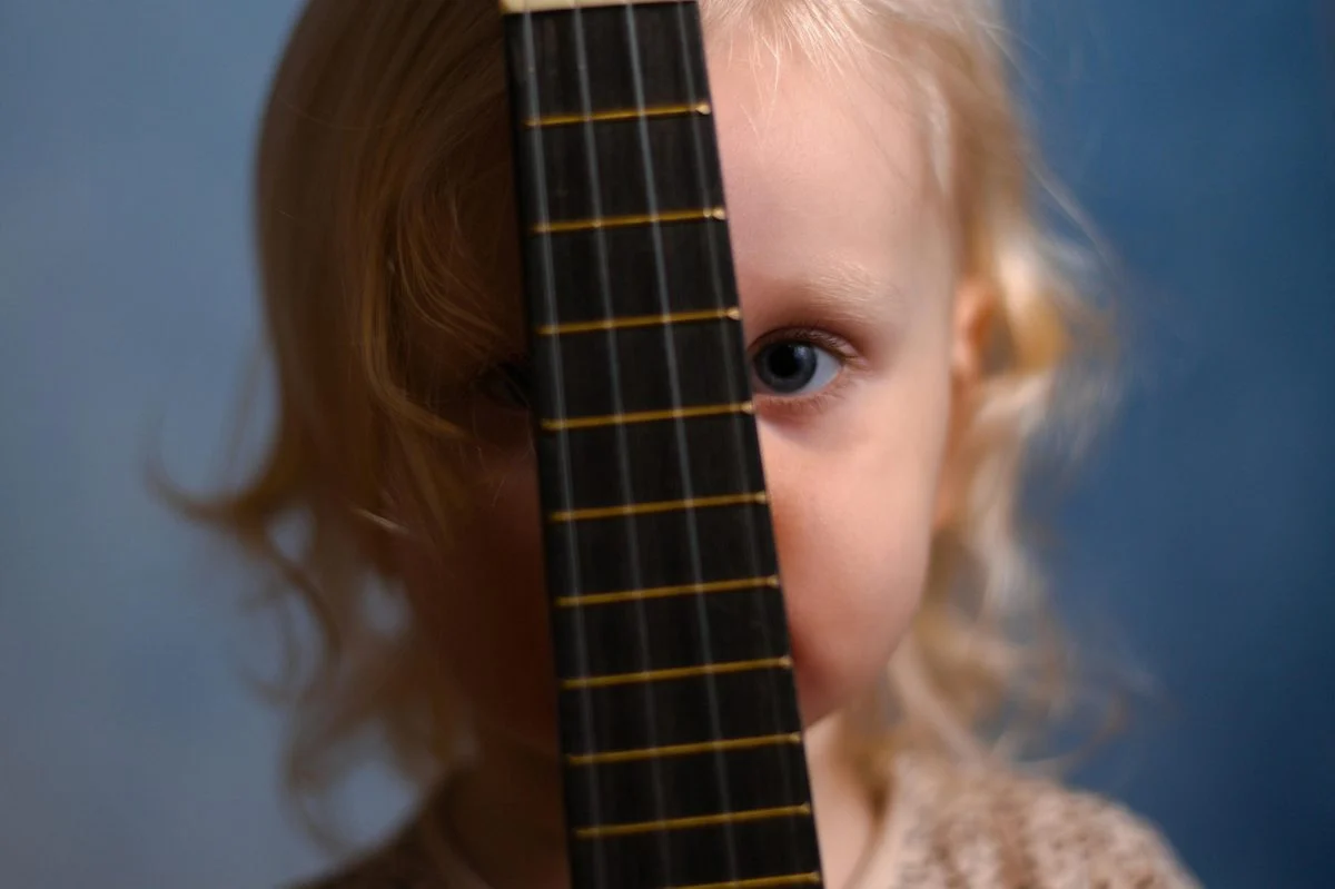 Toddler playing a small percussion instrument in a music class