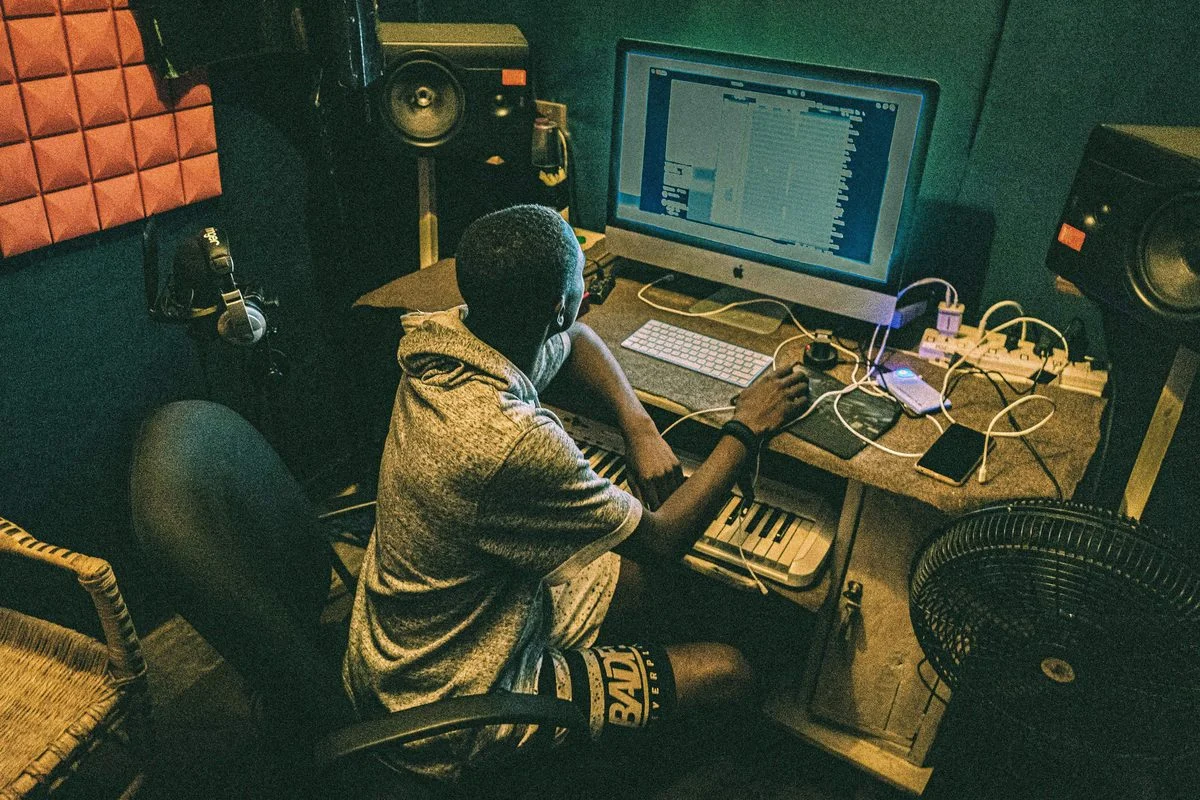 Music Production lesson — student and instructor at a studio workstation